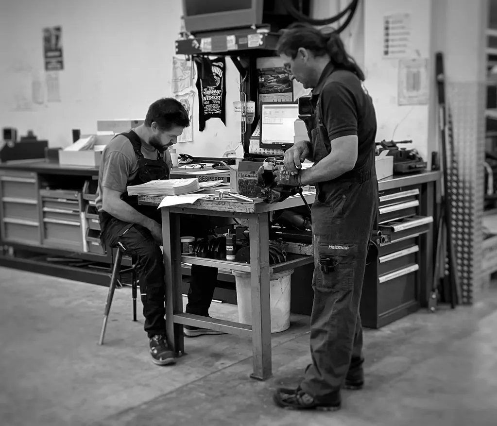 Zwei Arbeiter bei der Arbeit an einem Tisch in einer industriellen Werkstatt