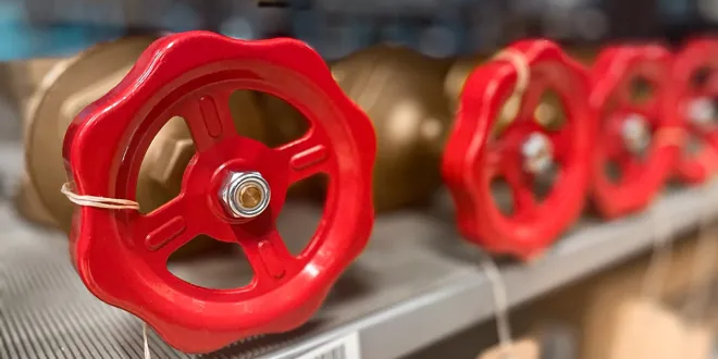 Rote Ventilräder und metallische Armaturen auf einem Regal in einem technischen Lagerbereich