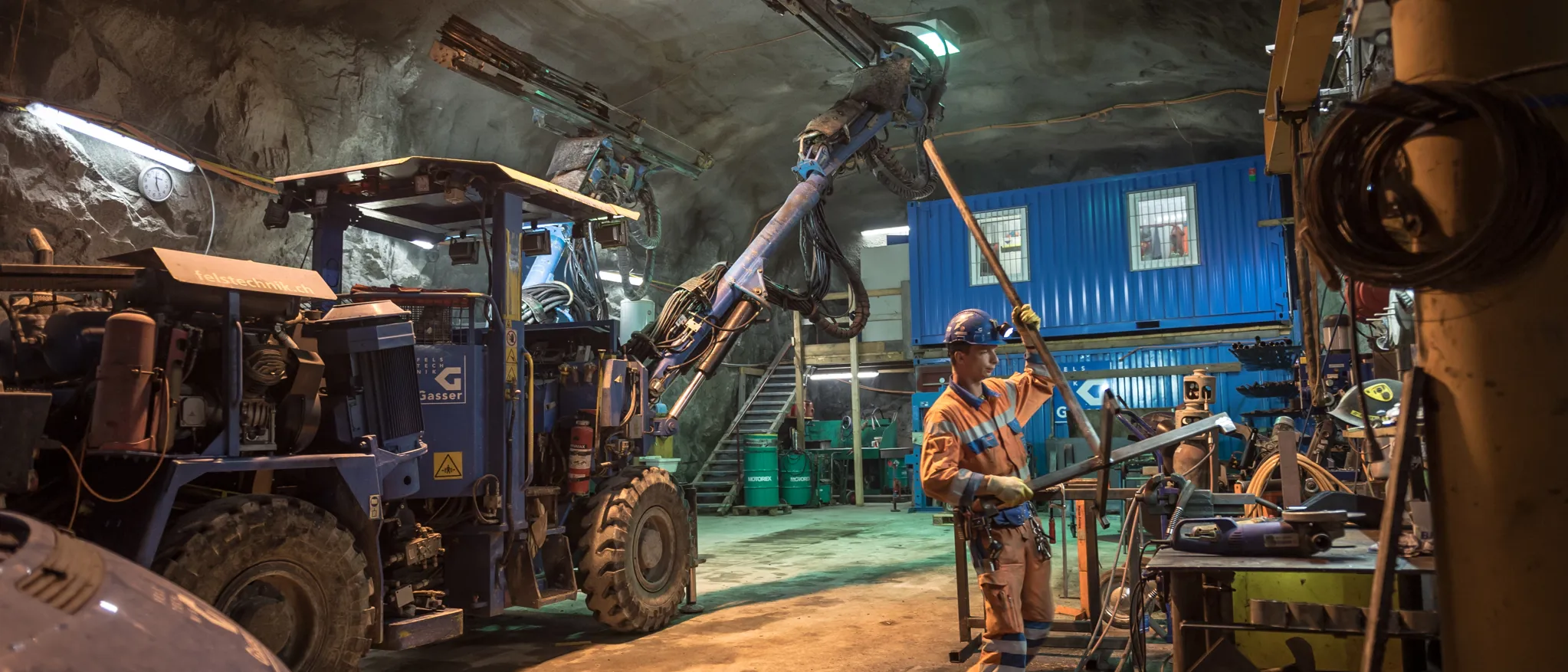 Ouvriers manipulant des machines et des véhicules dans un atelier souterrain éclairé