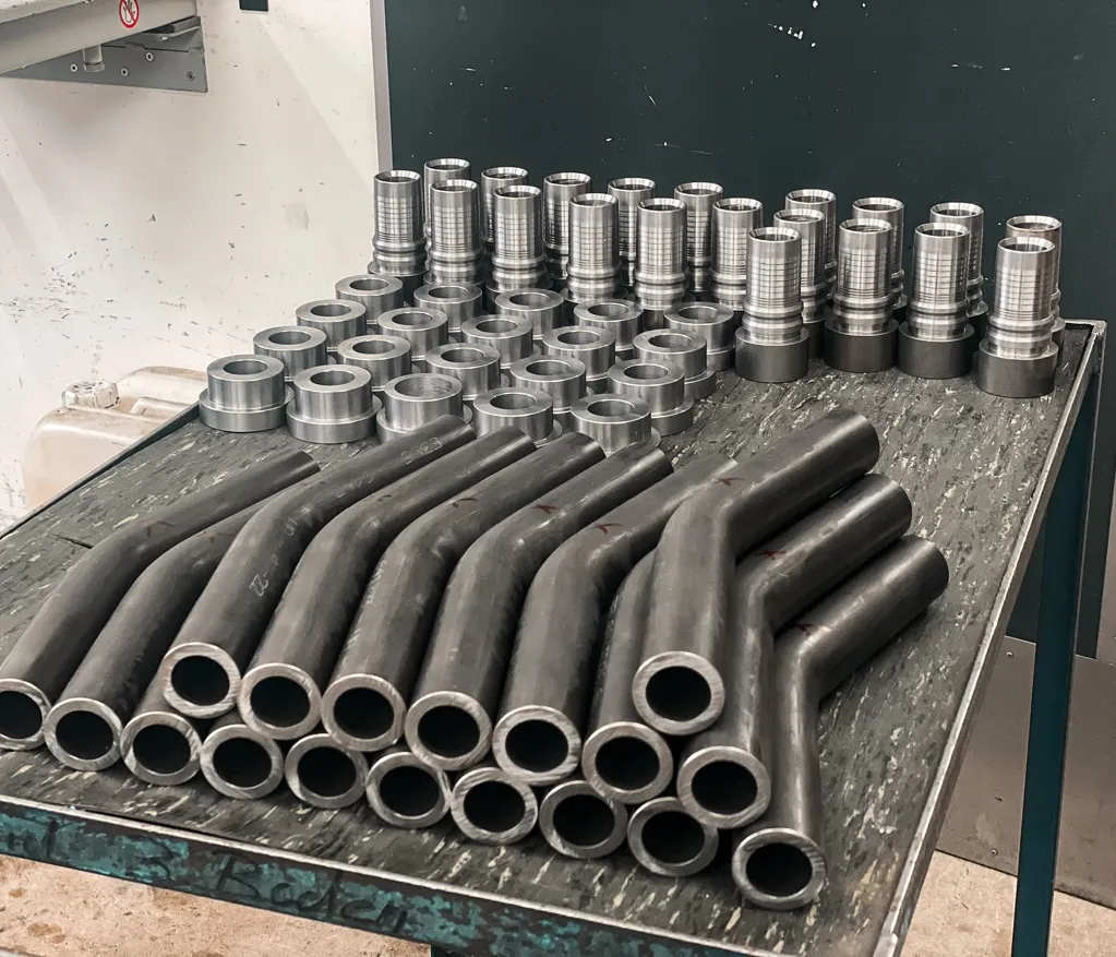 Collection organisée de tuyaux hydrauliques finis et de raccords métalliques sur une table
