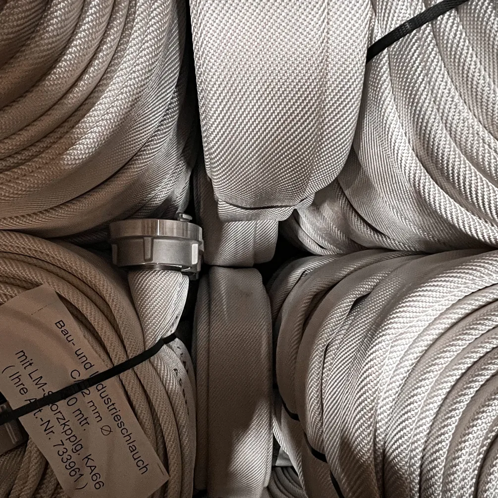 Tuyaux industriels blancs en faisceaux maintenus par des bandes noires et des étiquettes.