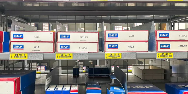 Étagères avec des boîtes bleues et rouges de différentes tailles étiquetées dans un stockage.