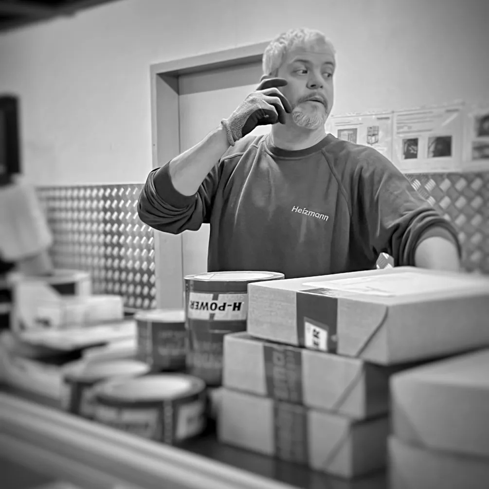 Employé en entrepôt parlant au téléphone et travaillant à une table d'expédition avec des colis